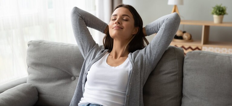 Optimale Verdauung: Frau sitzt entspannt auf dem Sofa.